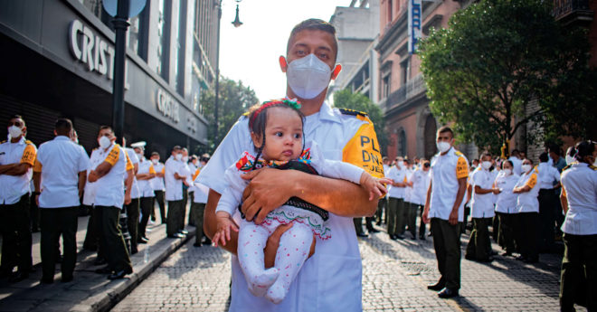 “Moreno”, de la Escuela Militar de Clase de Sanidad, carga a su bebé de 5 meses antes de presentarse a desfilar en el Zócalo